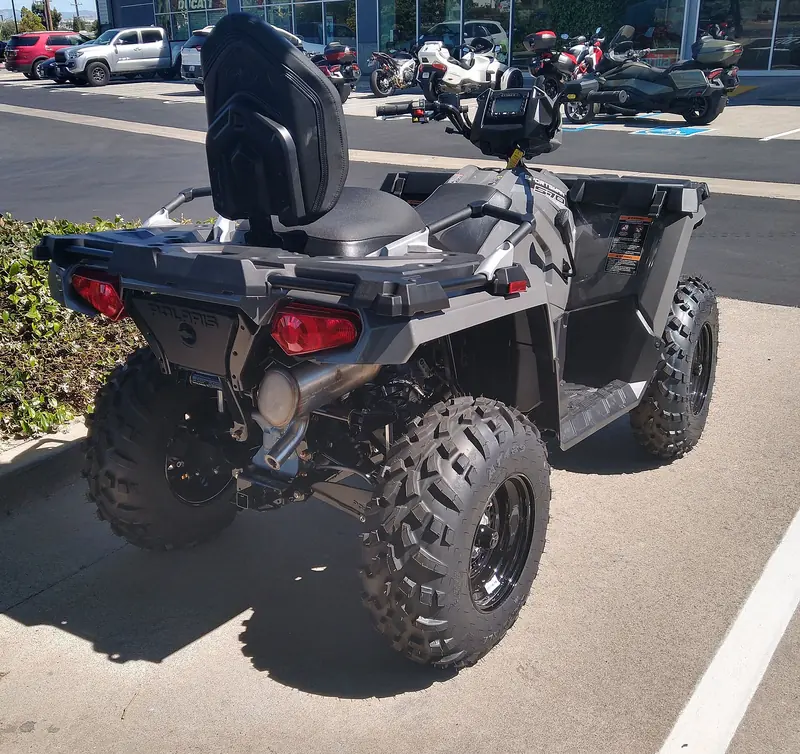 Rear three-quarter view of a black Polaris Sportsman 570 ATV with a rear seat back, parked outdoors