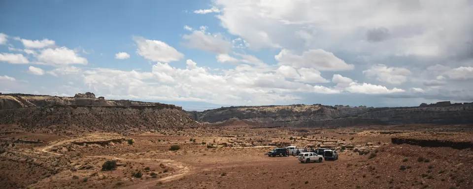 Several vehicles parked at a dispersed campsite on open desert in the San Rafael Swell, Utah
